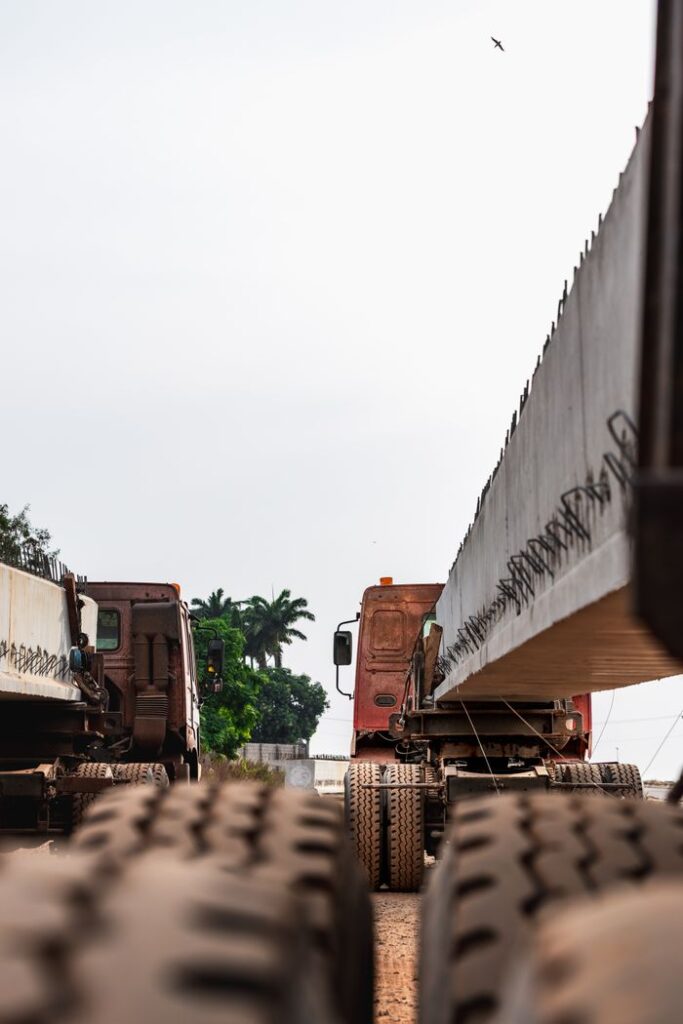 Heavy trucks transporting large concrete beams in Federal Capital Territory, Nigeria, showcasing industrial logistics.